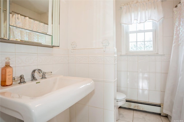 bathroom with toilet, sink, tile walls, and a baseboard heating unit