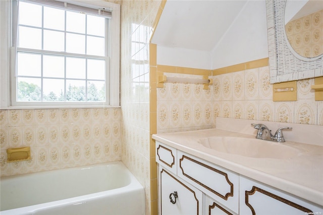 bathroom with vanity, a bath, and vaulted ceiling