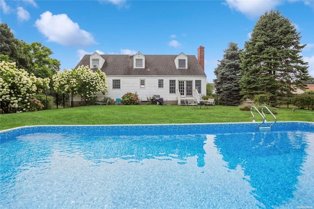 rear view of house with a fenced in pool and a lawn