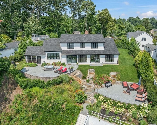 back of house with a lawn, a patio area, and an outdoor living space with a fire pit