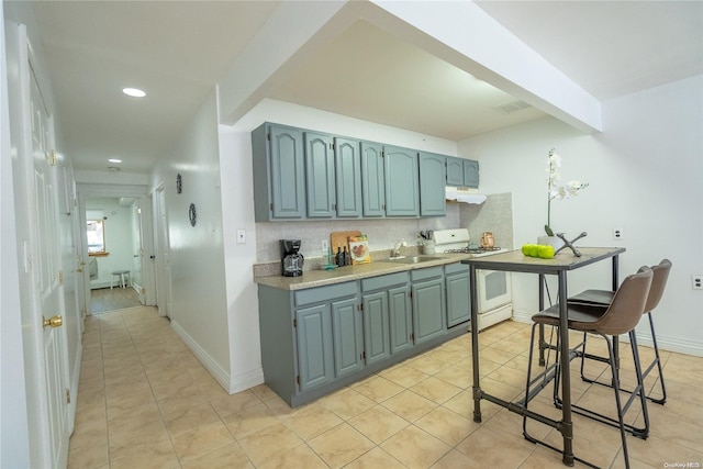 kitchen featuring beam ceiling, sink, white range with gas stovetop, backsplash, and light tile patterned floors