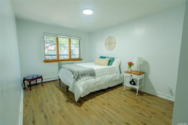 bedroom with a baseboard radiator and light hardwood / wood-style floors