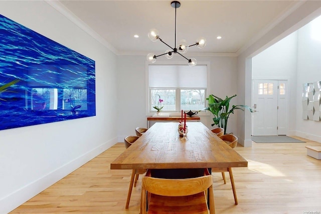 dining room featuring light wood-type flooring, ornamental molding, and an inviting chandelier