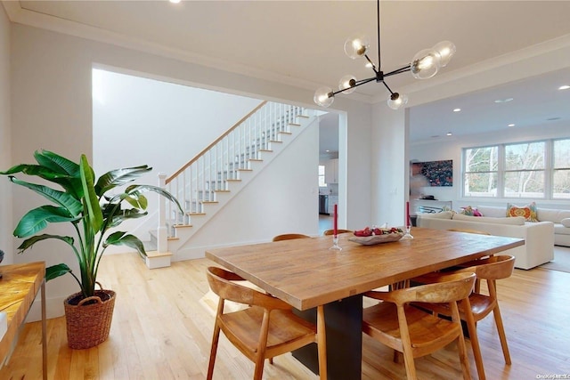 dining area with ornamental molding, a chandelier, and light wood-type flooring