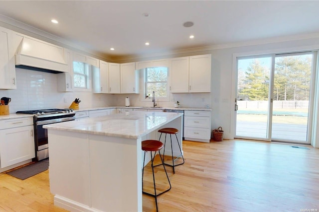 kitchen featuring gas range, white cabinetry, a kitchen island, and light wood-type flooring