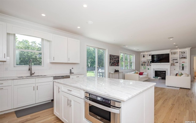 kitchen featuring white cabinetry, sink, a center island, and light hardwood / wood-style flooring