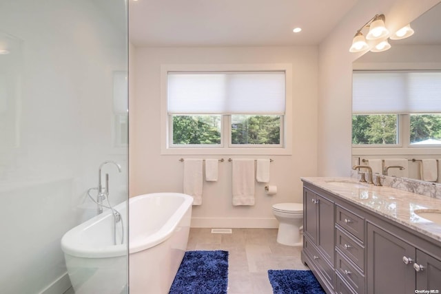 bathroom with tile patterned floors, a bathtub, plenty of natural light, and vanity