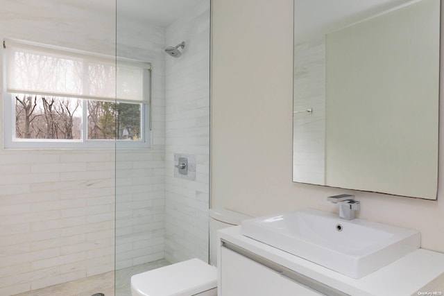 bathroom featuring vanity, toilet, and tiled shower