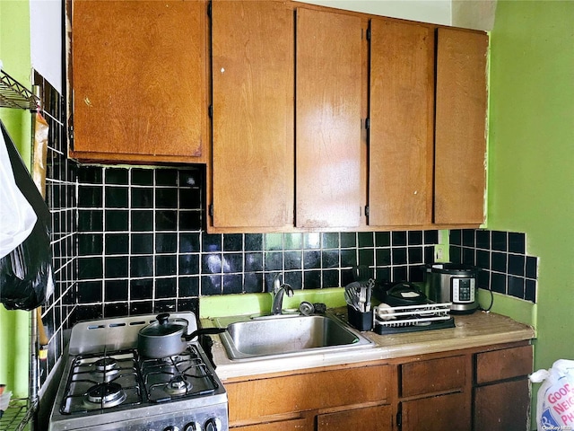 kitchen with decorative backsplash, stove, and sink