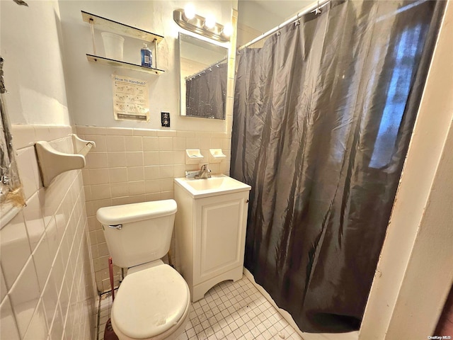 bathroom featuring tile patterned floors, vanity, toilet, and tile walls