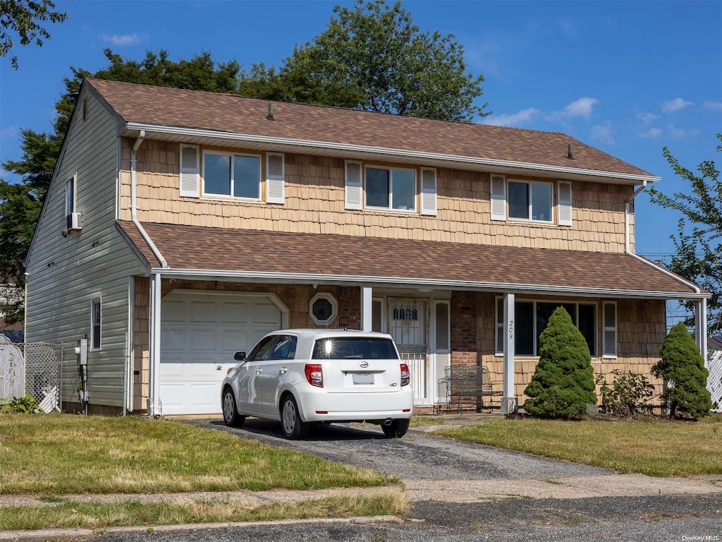 view of front of home with covered porch, a garage, and a front lawn