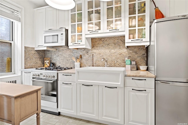 kitchen featuring white appliances, white cabinets, sink, light stone countertops, and tasteful backsplash