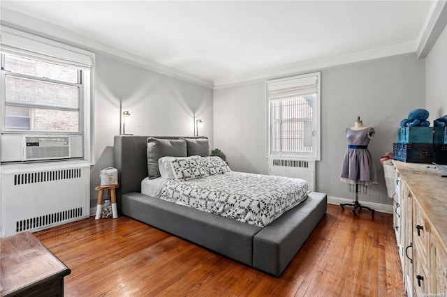 bedroom with radiator heating unit, dark hardwood / wood-style floors, and ornamental molding