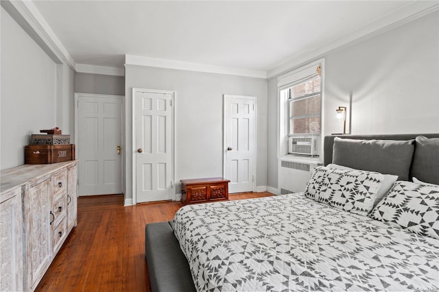 bedroom featuring dark wood-type flooring, radiator, cooling unit, crown molding, and multiple closets