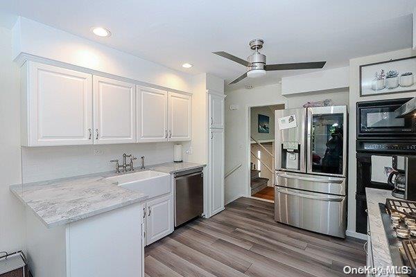 kitchen with black appliances, ceiling fan, light stone counters, light hardwood / wood-style flooring, and white cabinetry