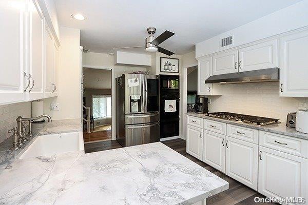 kitchen with white cabinets, stainless steel appliances, tasteful backsplash, and sink