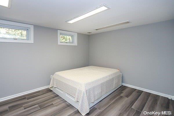 bedroom with dark wood-type flooring and multiple windows