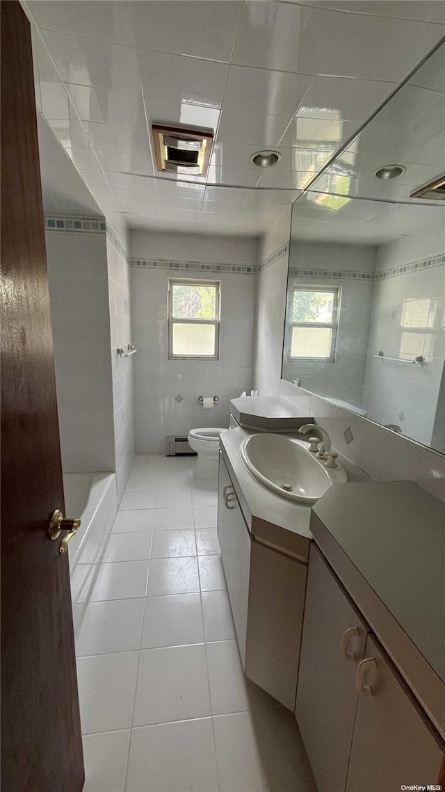 bathroom with tile patterned floors, a healthy amount of sunlight, toilet, and tile walls