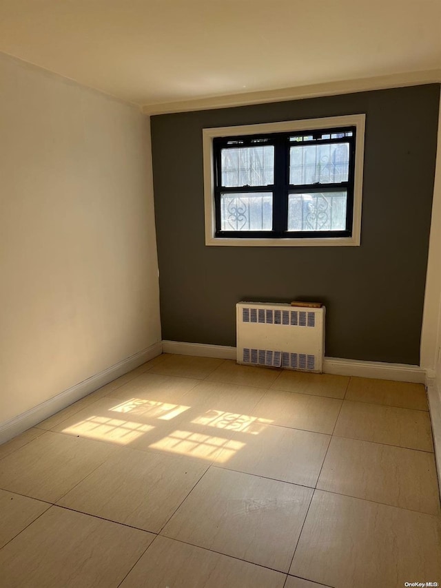 spare room with radiator heating unit and light tile patterned floors