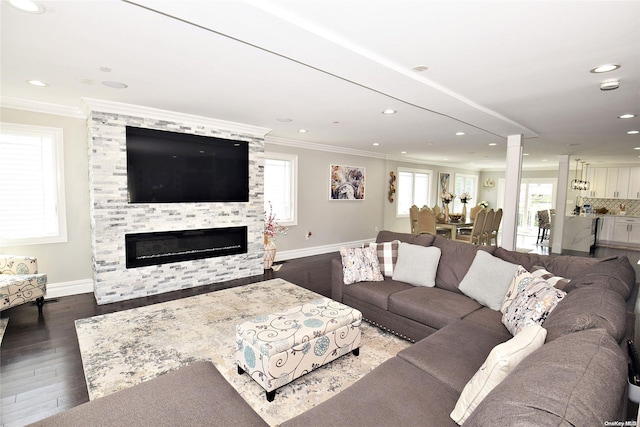 living room with dark wood-type flooring, ornamental molding, and a stone fireplace