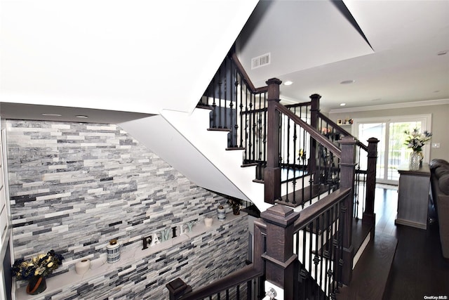 stairway with ornamental molding and hardwood / wood-style flooring