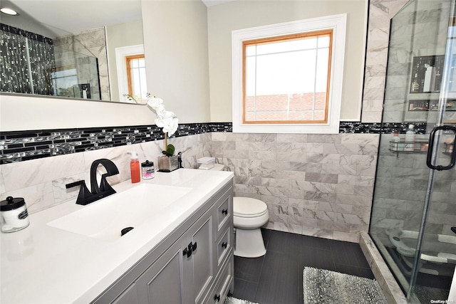 bathroom with toilet, a shower with door, tile walls, tile patterned floors, and vanity