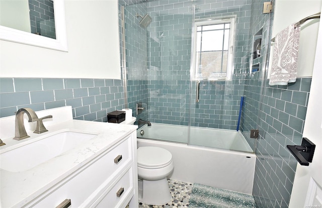 full bathroom featuring tile patterned flooring, vanity, bath / shower combo with glass door, tile walls, and toilet