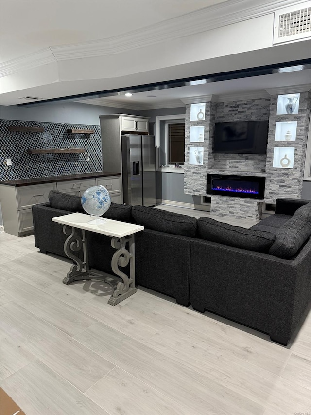 living room with a large fireplace, crown molding, and light hardwood / wood-style floors