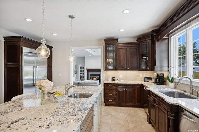kitchen featuring light stone countertops, appliances with stainless steel finishes, hanging light fixtures, and sink