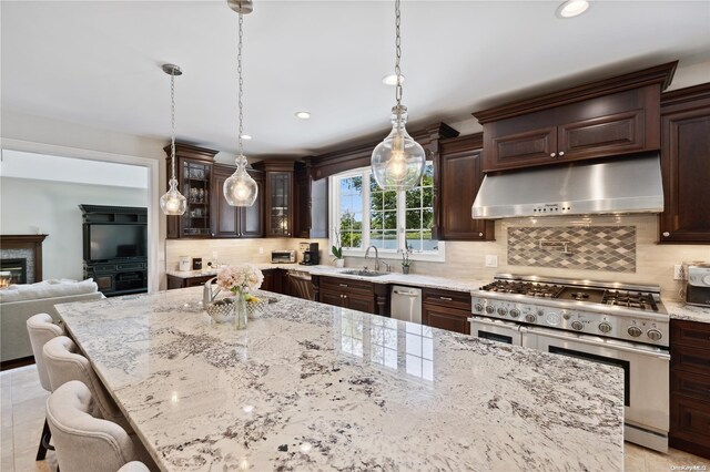 kitchen featuring hanging light fixtures, stainless steel appliances, light stone counters, backsplash, and a kitchen bar