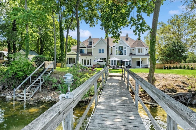 back of property with a water view and a yard