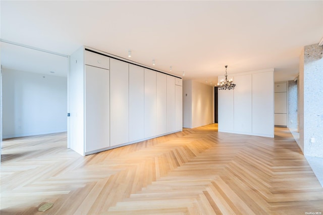 unfurnished room with light parquet flooring and a notable chandelier