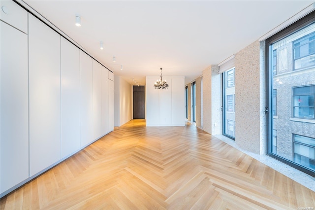 unfurnished room with light parquet flooring, plenty of natural light, and a notable chandelier