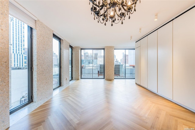 unfurnished room featuring a healthy amount of sunlight, a wall of windows, and light parquet floors