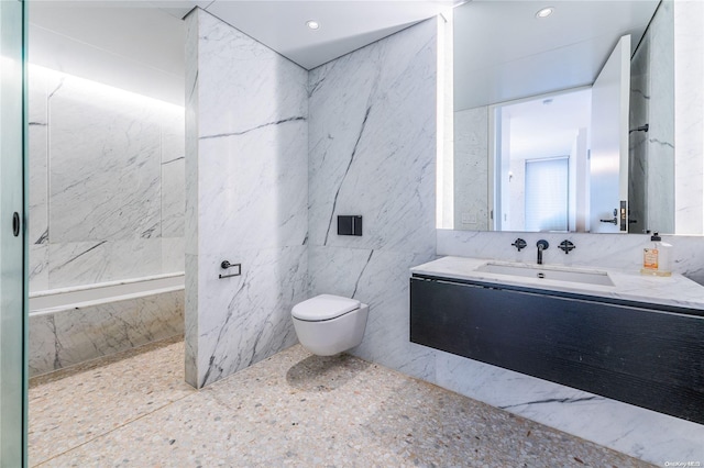 bathroom with tiled shower, vanity, toilet, and tile walls