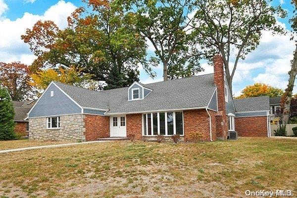 cape cod house with central AC unit and a front lawn