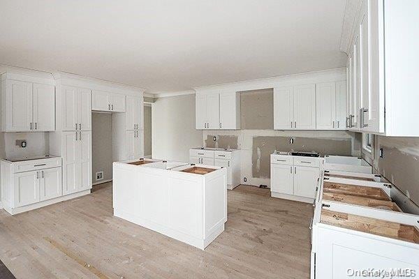 127 Berkshire Rd, Rockville Centre, NY 11570 - kitchen with light wood finished floors, a center island, and white cabinets