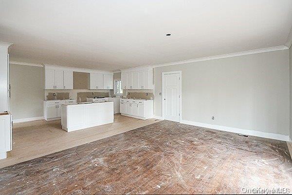 127 Berkshire Rd, Rockville Centre, NY 11570 - kitchen with crown molding, a kitchen island, white cabinetry, open floor plan, and light wood-style floors
