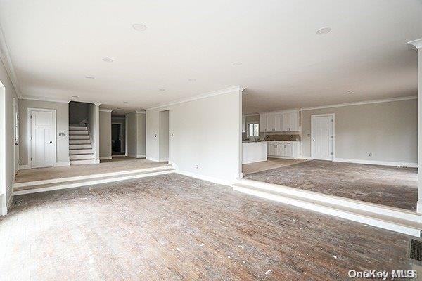 127 Berkshire Rd, Rockville Centre, NY 11570 - unfurnished living room with crown molding, stairs, and wood finished floors