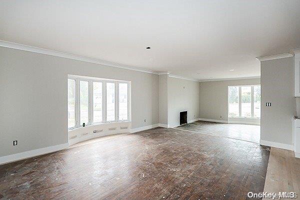 unfurnished living room featuring hardwood / wood-style floors and ornamental molding