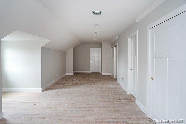 bonus room featuring light wood-type flooring and vaulted ceiling