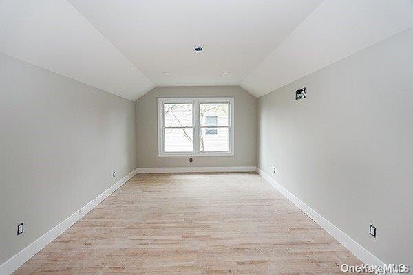 bonus room with vaulted ceiling and light wood-type flooring