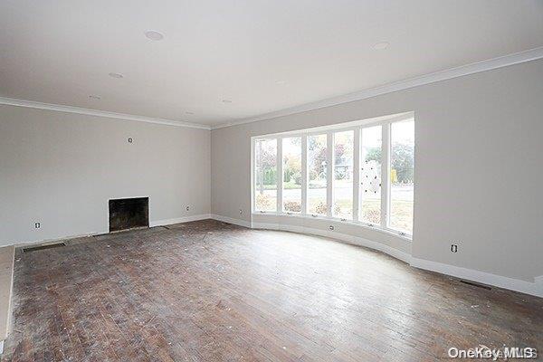 unfurnished living room featuring wood-type flooring and ornamental molding