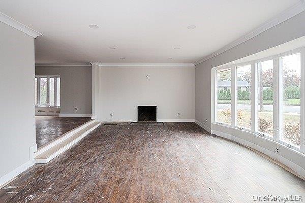 127 Berkshire Rd, Rockville Centre, NY 11570 - unfurnished living room featuring a fireplace, wood finished floors, and crown molding