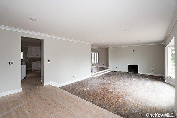127 Berkshire Rd, Rockville Centre, NY 11570 - unfurnished living room with wood finished floors, ornamental molding, and a fireplace
