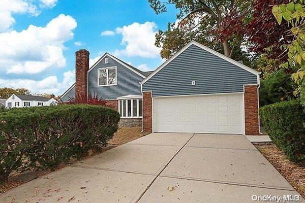 127 Berkshire Rd, Rockville Centre, NY 11570 - view of home's exterior with concrete driveway, a chimney, brick siding, and an attached garage