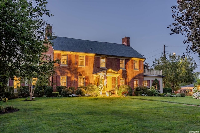 colonial inspired home featuring a lawn and a balcony