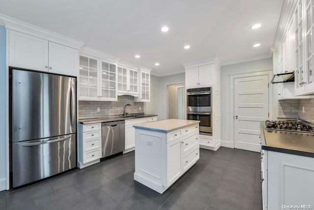 kitchen featuring a center island, stainless steel appliances, backsplash, white cabinets, and ornamental molding