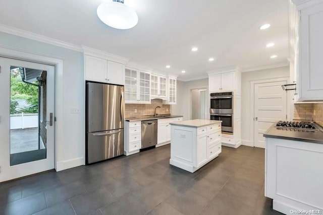 kitchen featuring backsplash, white cabinetry, a kitchen island, and stainless steel appliances