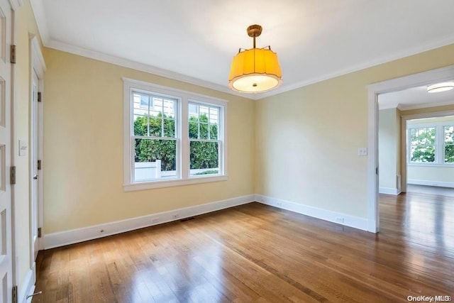 empty room with plenty of natural light, ornamental molding, and dark wood-type flooring